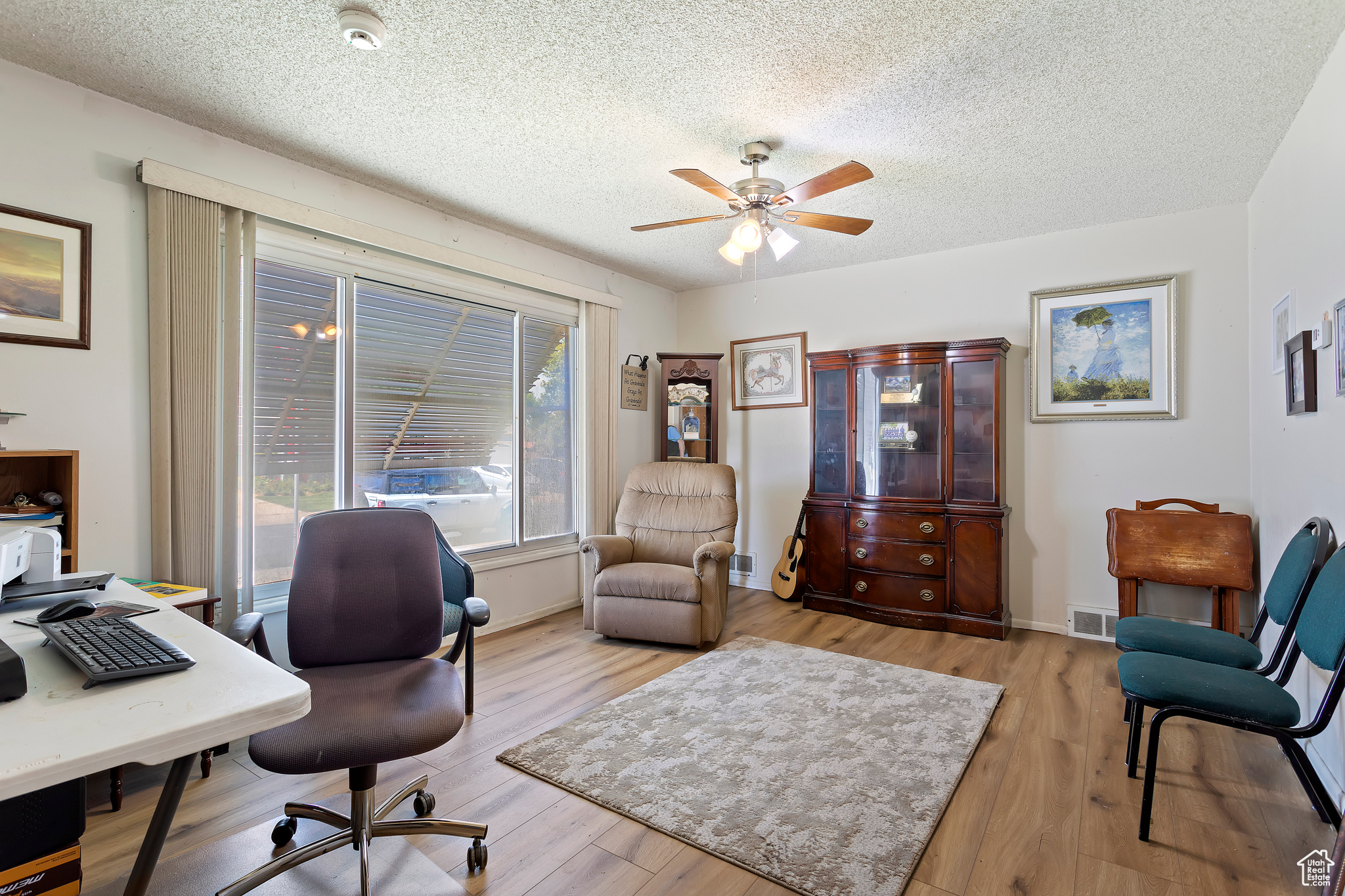 Office space featuring a textured ceiling, ceiling fan, and light wood-type flooring