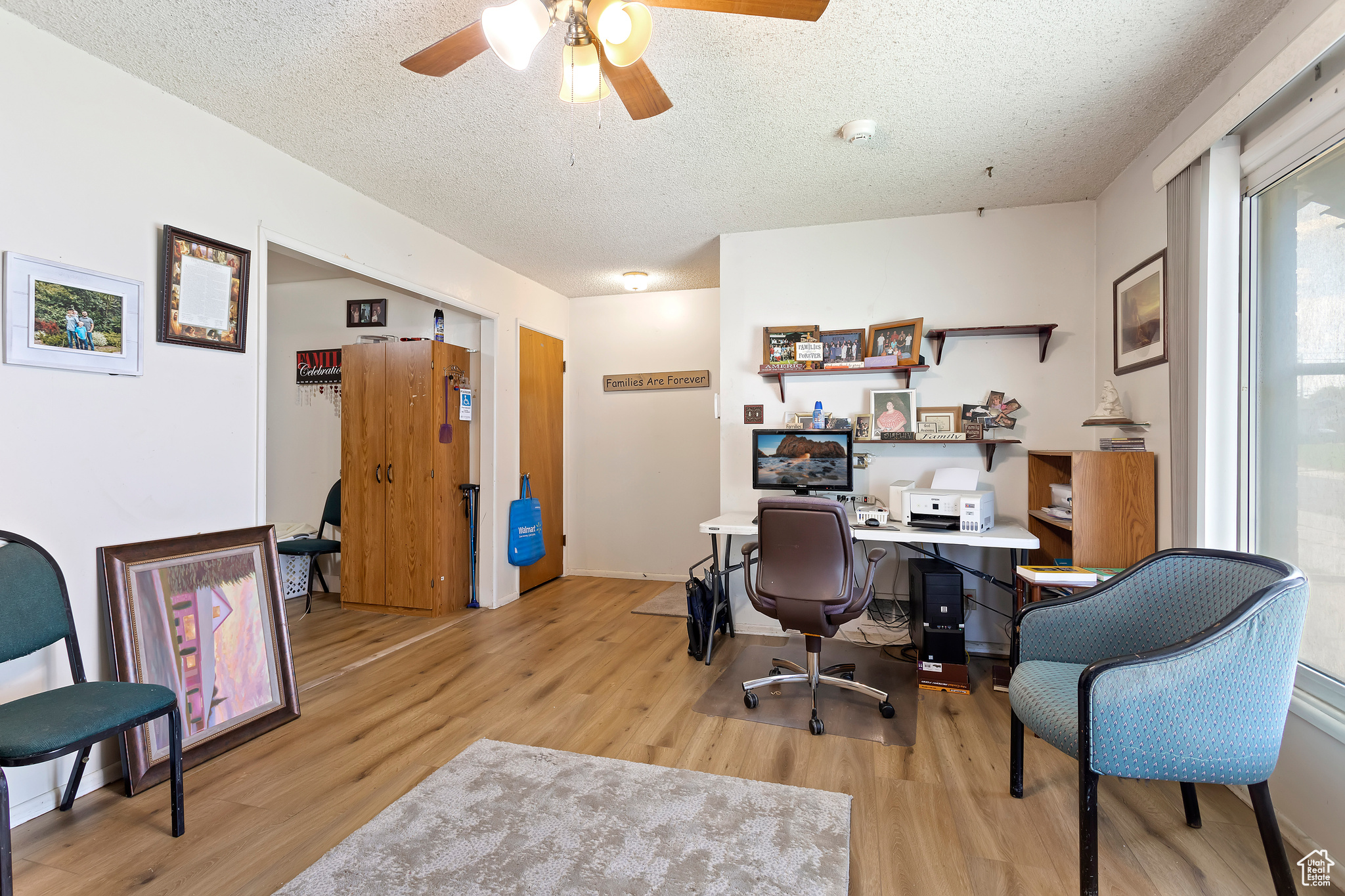 Office area with a textured ceiling, ceiling fan, and light hardwood / wood-style floors