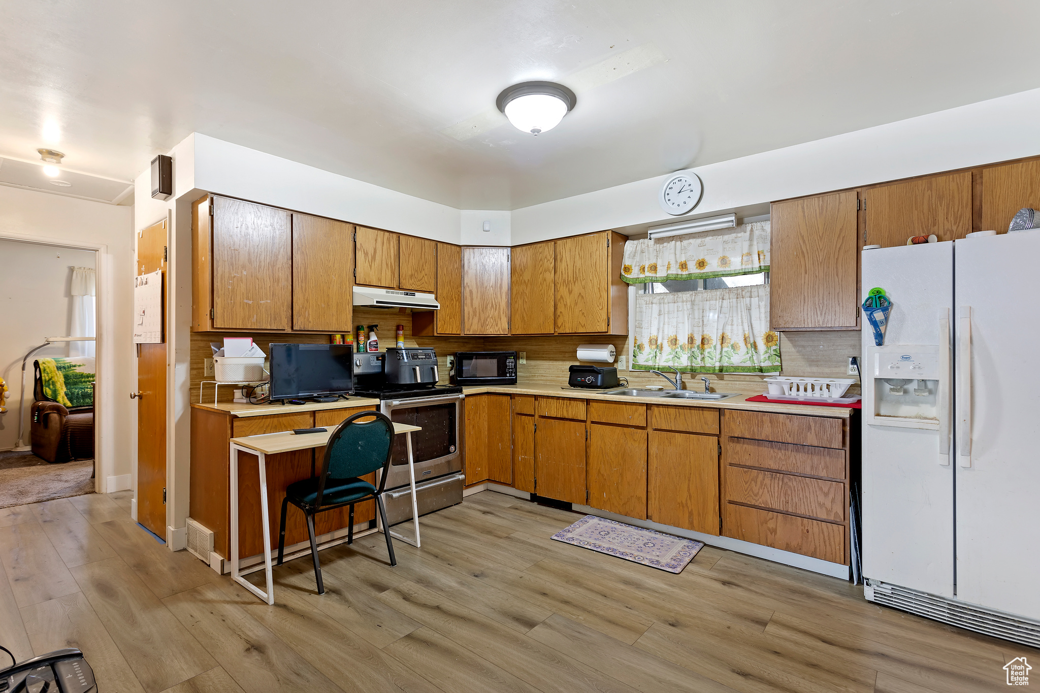 Kitchen featuring light wood-type flooring, electric range, tasteful backsplash, and white fridge with ice dispenser