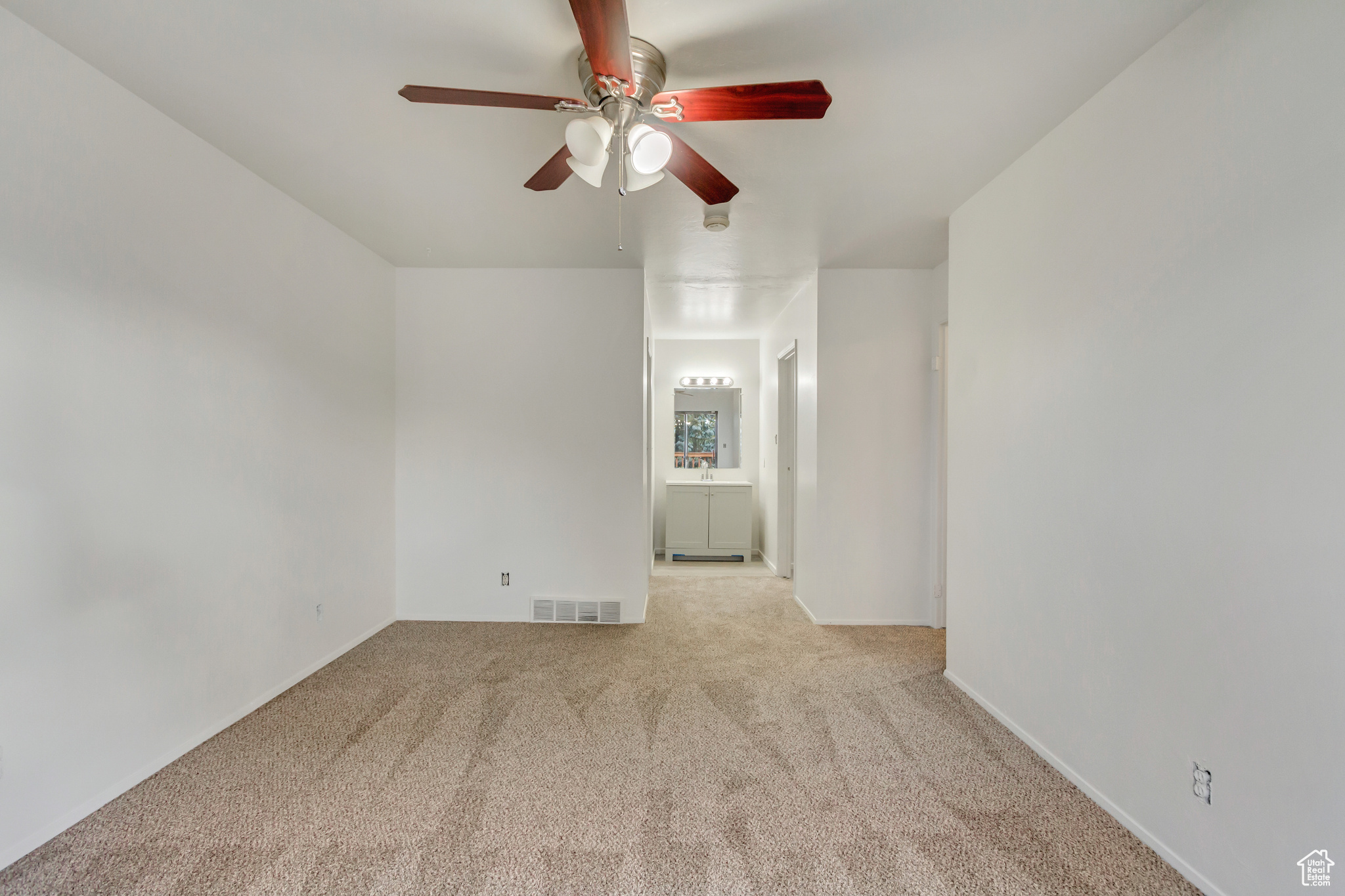 Spare room featuring light carpet and ceiling fan