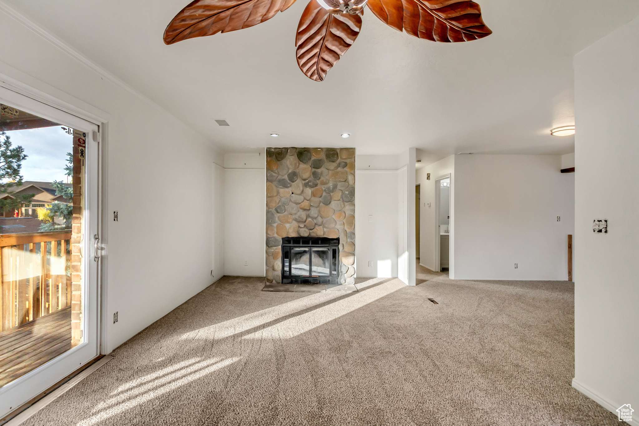 Unfurnished living room featuring a stone fireplace and carpet floors