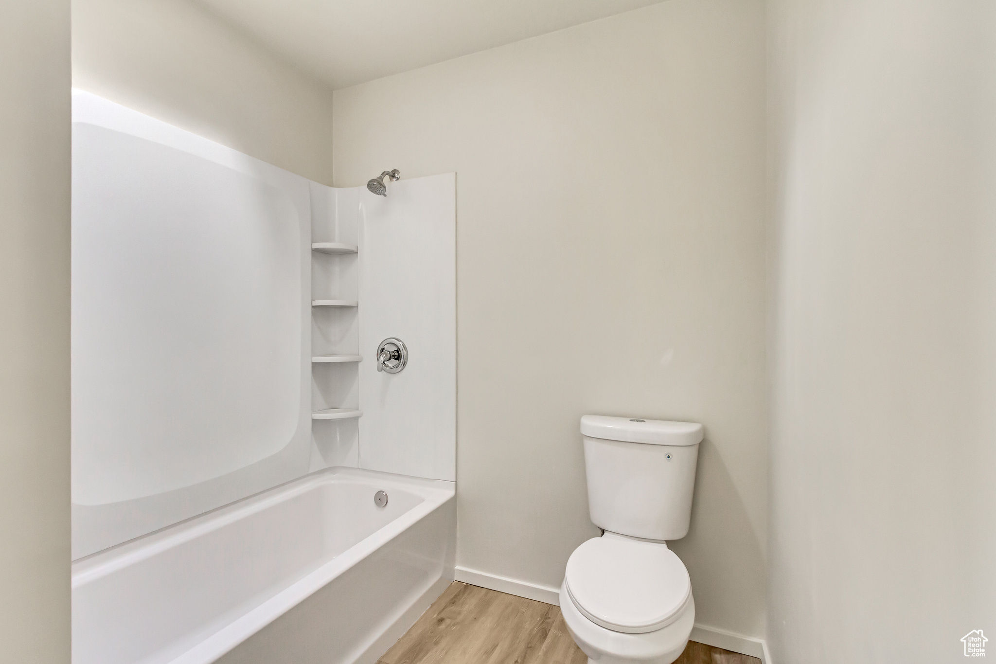 Bathroom featuring washtub / shower combination, hardwood / wood-style flooring, and toilet