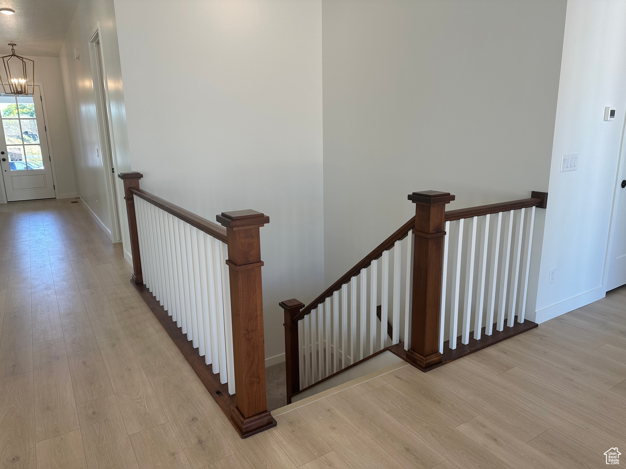 Stairs with a notable chandelier and hardwood / wood-style flooring