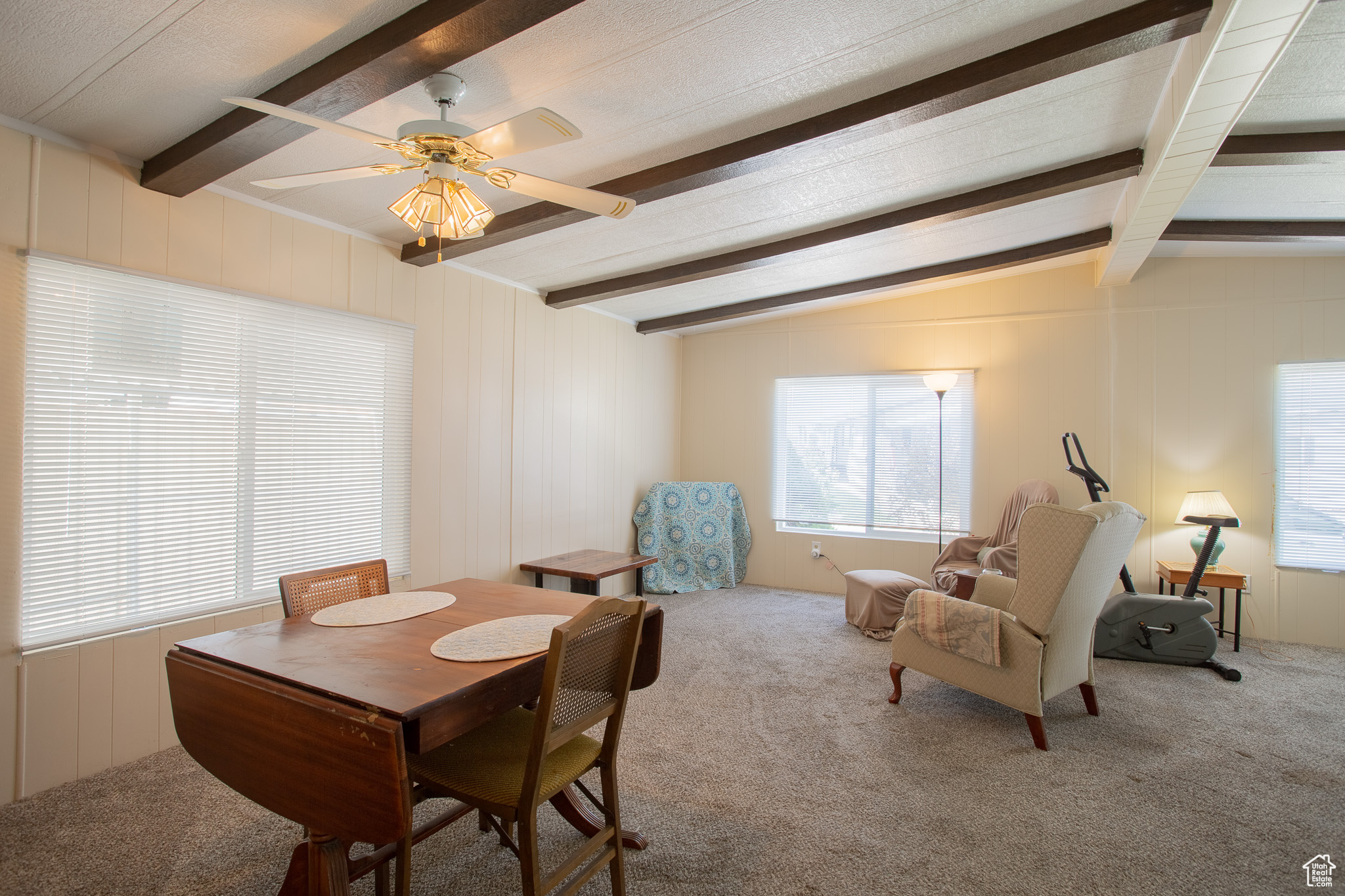 Dining space with vaulted ceiling with beams, carpet floors, and ceiling fan