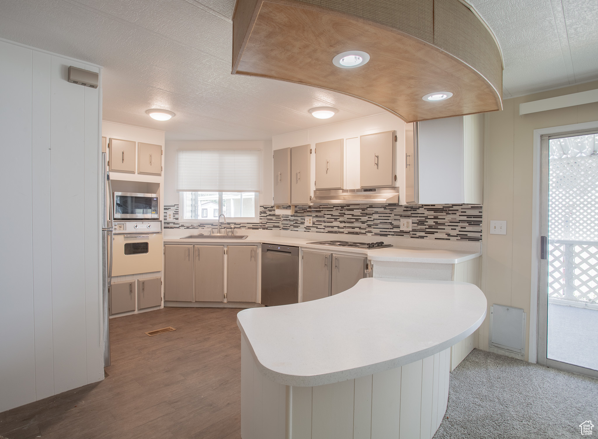 Kitchen with tasteful backsplash, stainless steel appliances, hardwood / wood-style floors, sink, and kitchen peninsula