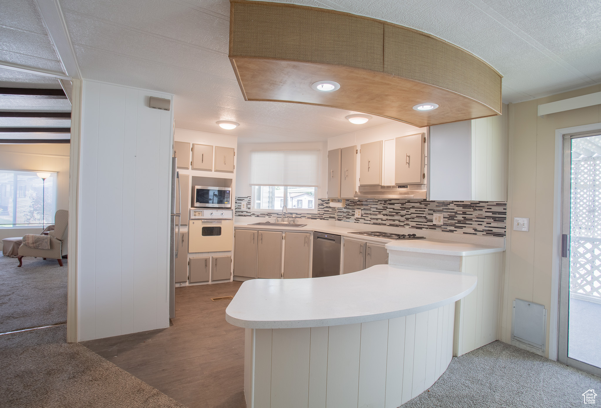 Kitchen featuring tasteful backsplash, stainless steel appliances, hardwood / wood-style floors, sink, and kitchen peninsula