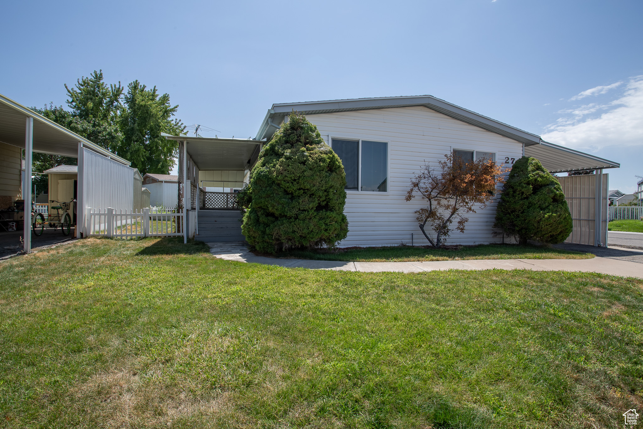 View of property exterior with a carport and a lawn