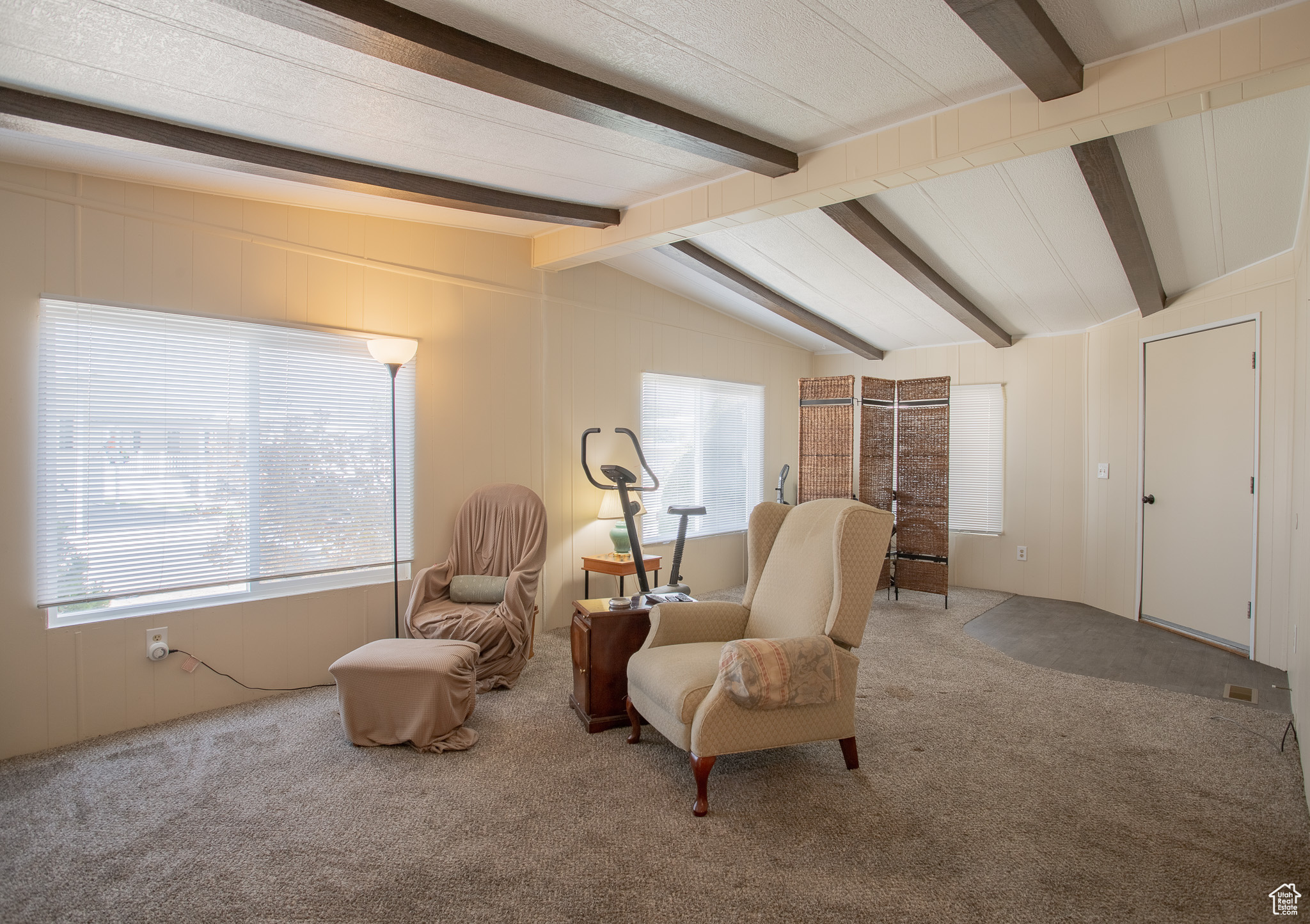 Living area with carpet and vaulted ceiling with beams