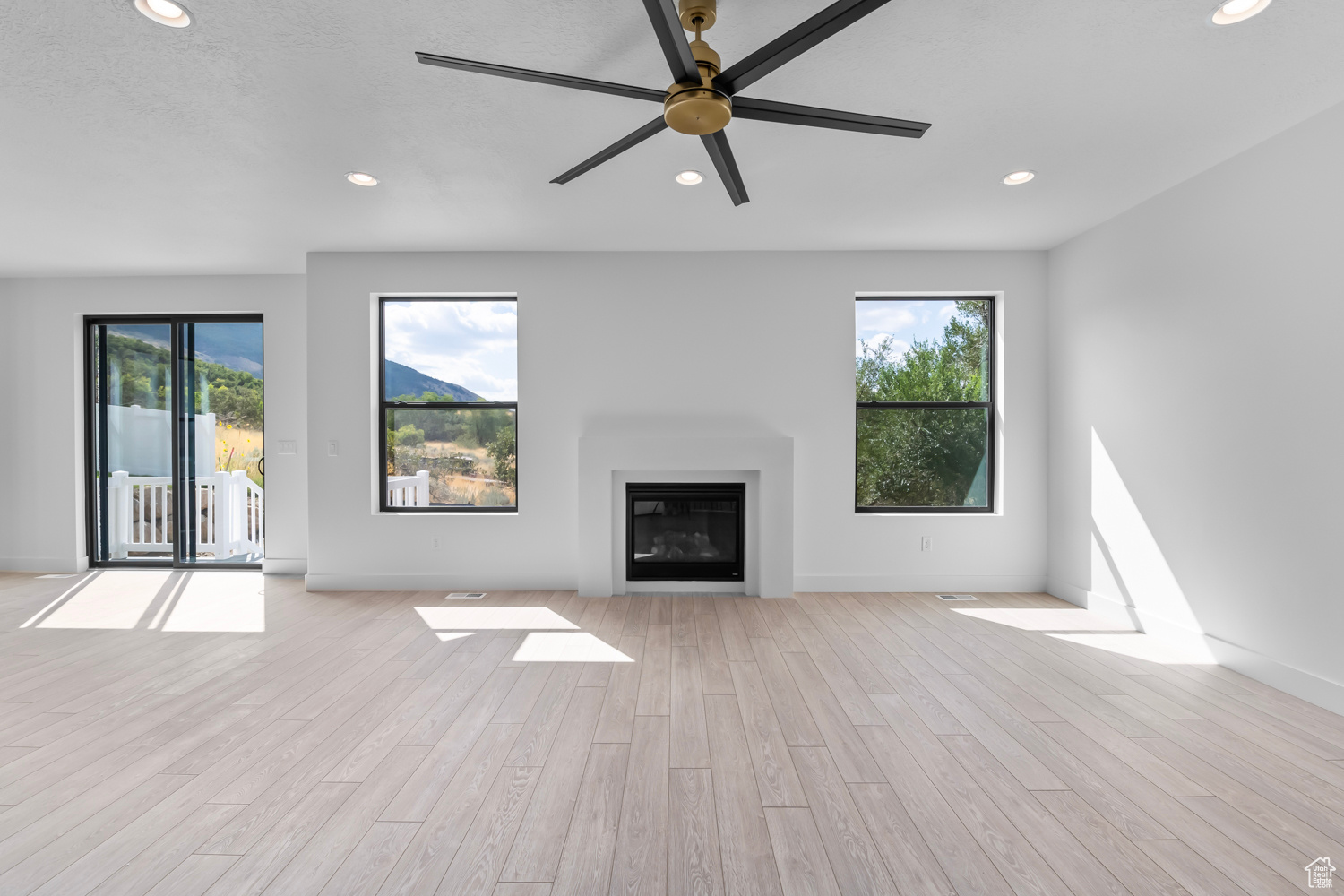 Unfurnished living room with a wealth of natural light, ceiling fan, and light hardwood / wood-style floors