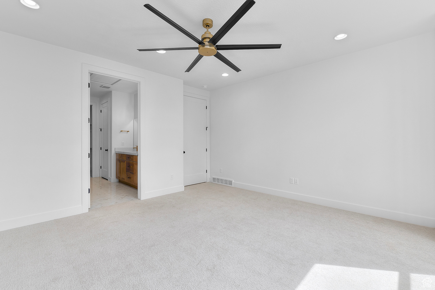 Unfurnished bedroom with light carpet, ensuite bath, and ceiling fan