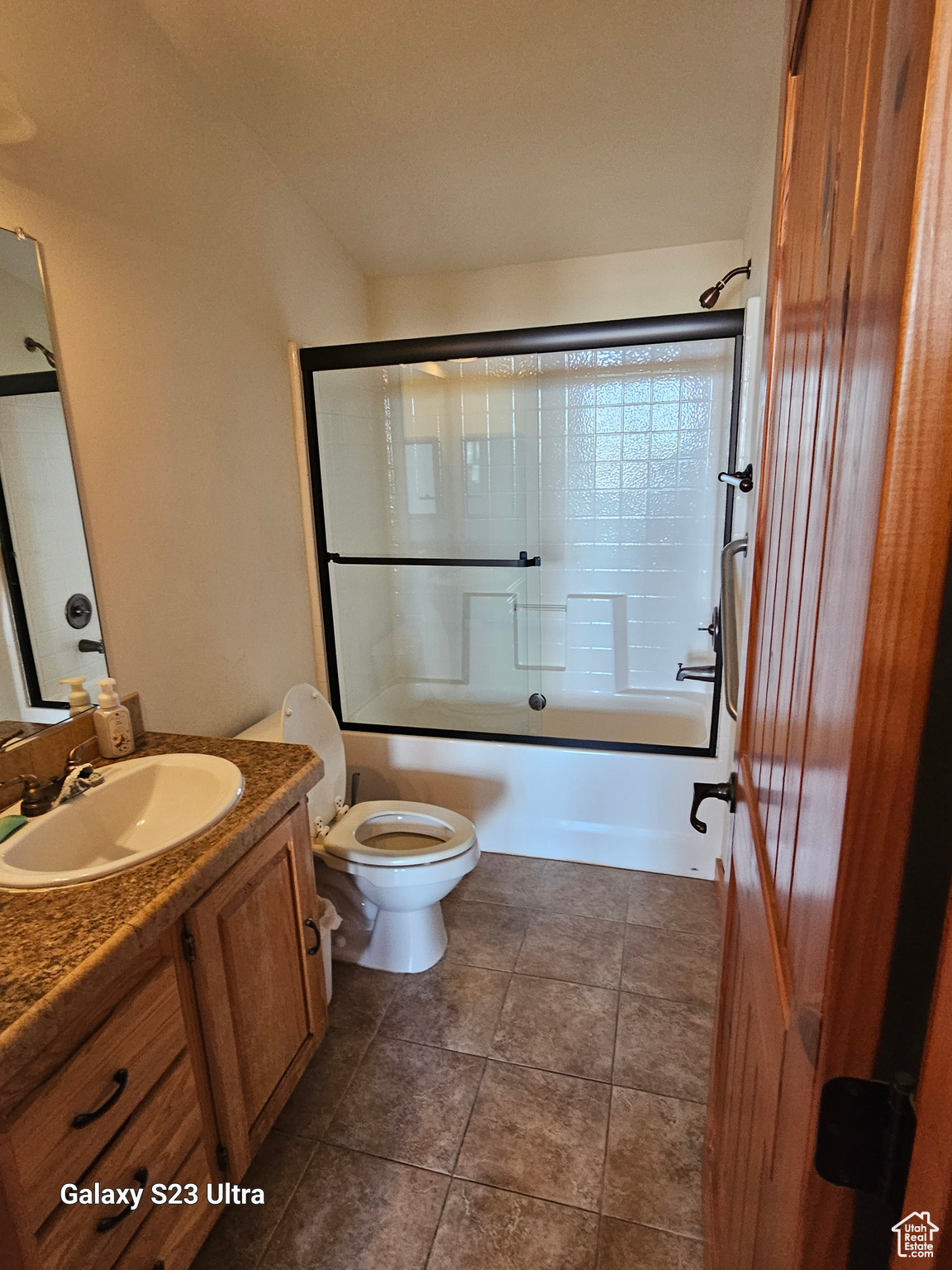 Full bathroom featuring vanity, toilet, tile patterned floors, and bath / shower combo with glass door