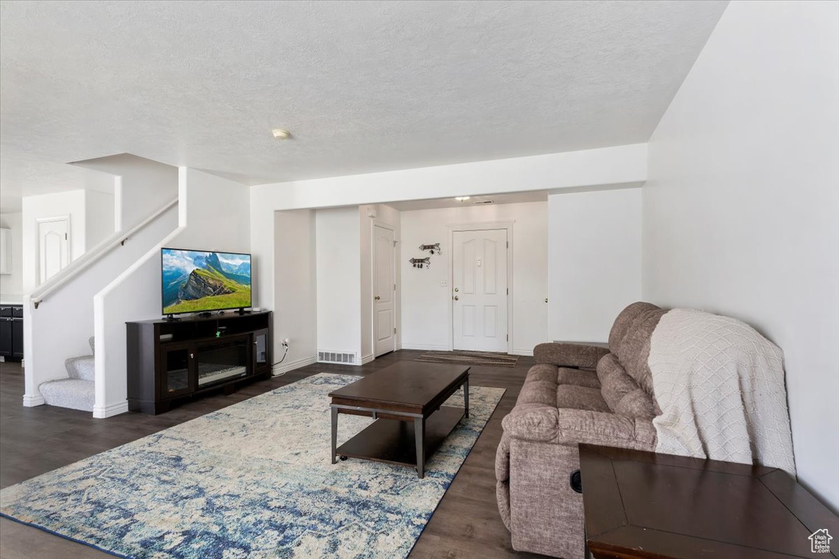 Living room featuring a textured ceiling and dark hardwood / wood-style flooring