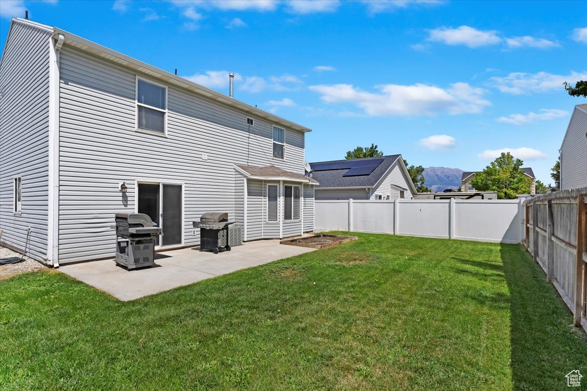 Rear view of property featuring a patio, a lawn, and solar panels