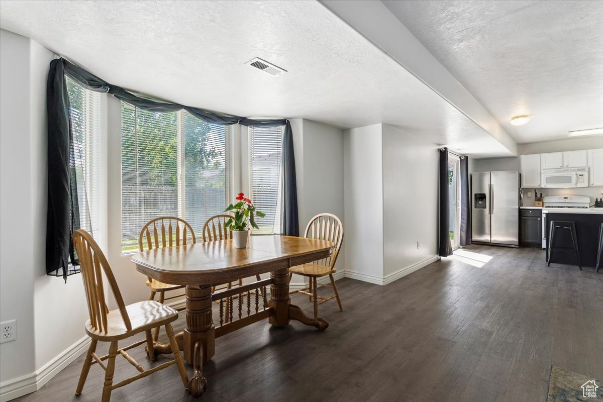 Dining area with dark hardwood / wood-style floors and a textured ceiling