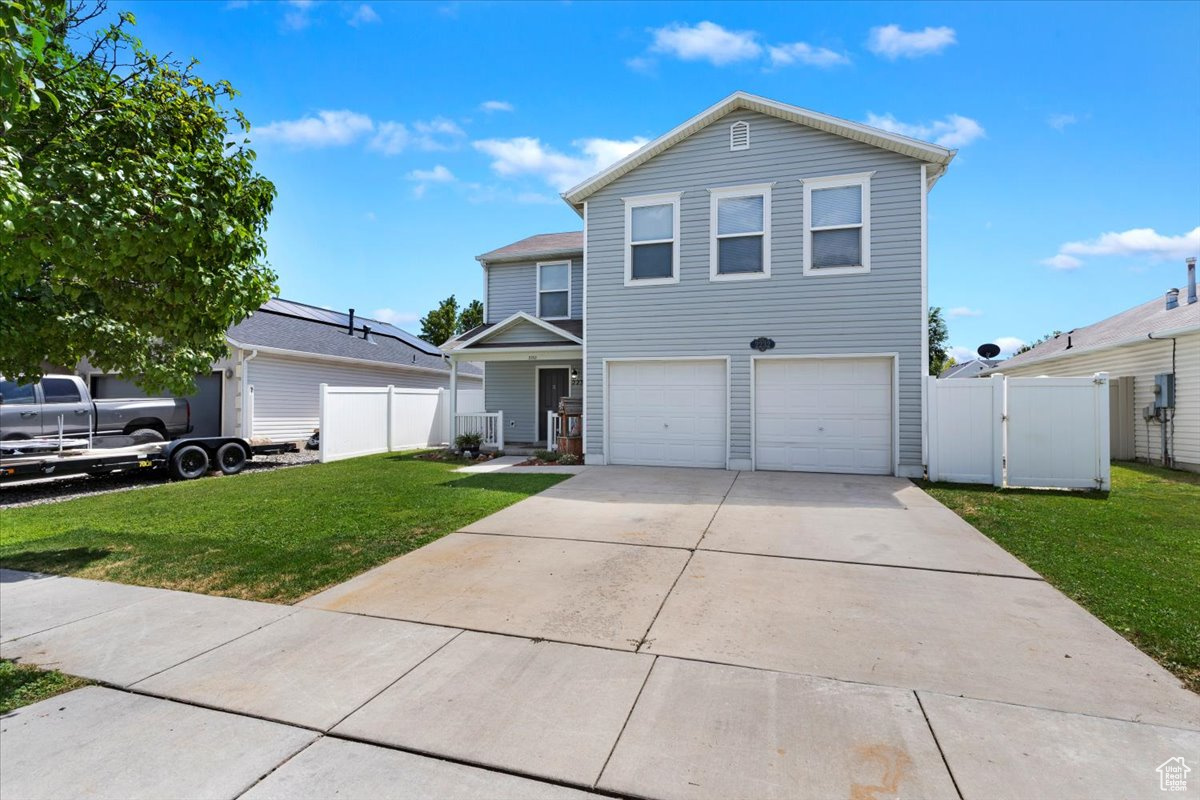 View of front of property featuring a garage and a front lawn