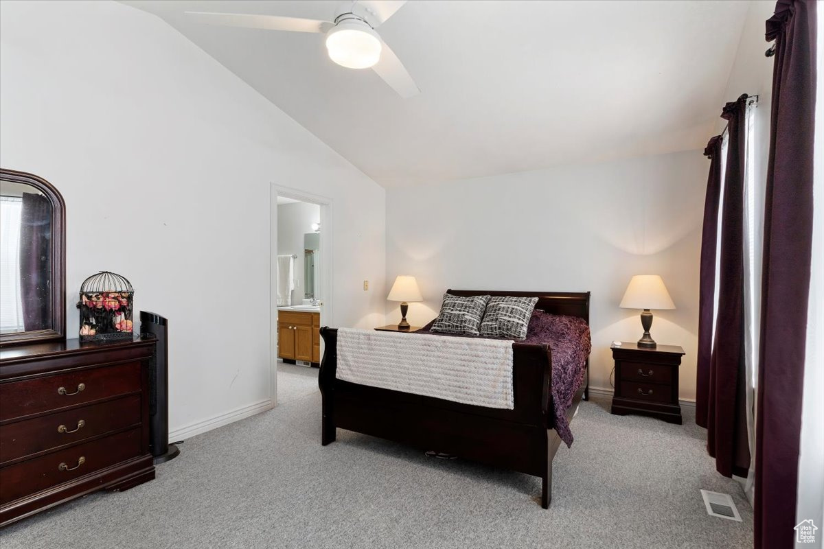 Carpeted bedroom featuring ensuite bathroom, lofted ceiling, and ceiling fan