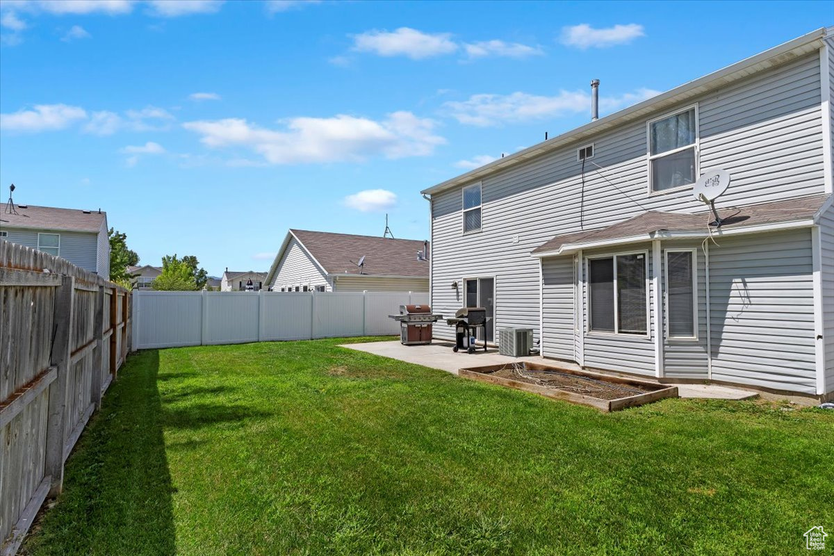 Back of house with central AC unit, a patio, and a lawn