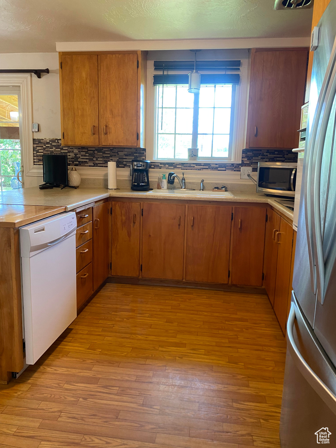 Kitchen with tasteful backsplash, light hardwood / wood-style flooring, appliances with stainless steel finishes, and sink