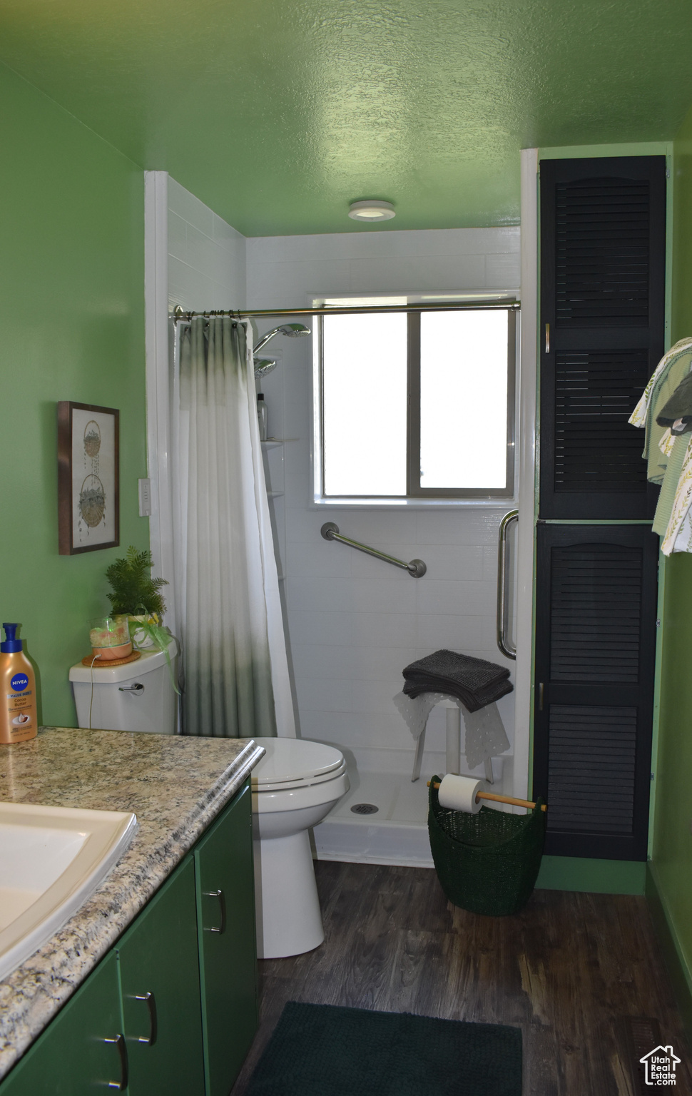 Bathroom featuring vanity, hardwood / wood-style floors, curtained shower, toilet, and a textured ceiling