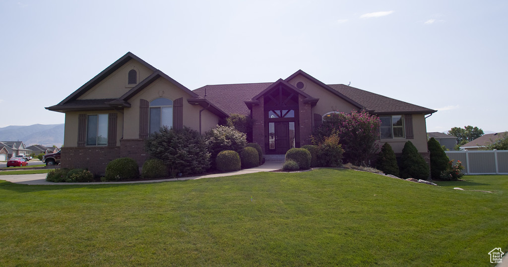 View of front of home with a mountain view and a front lawn