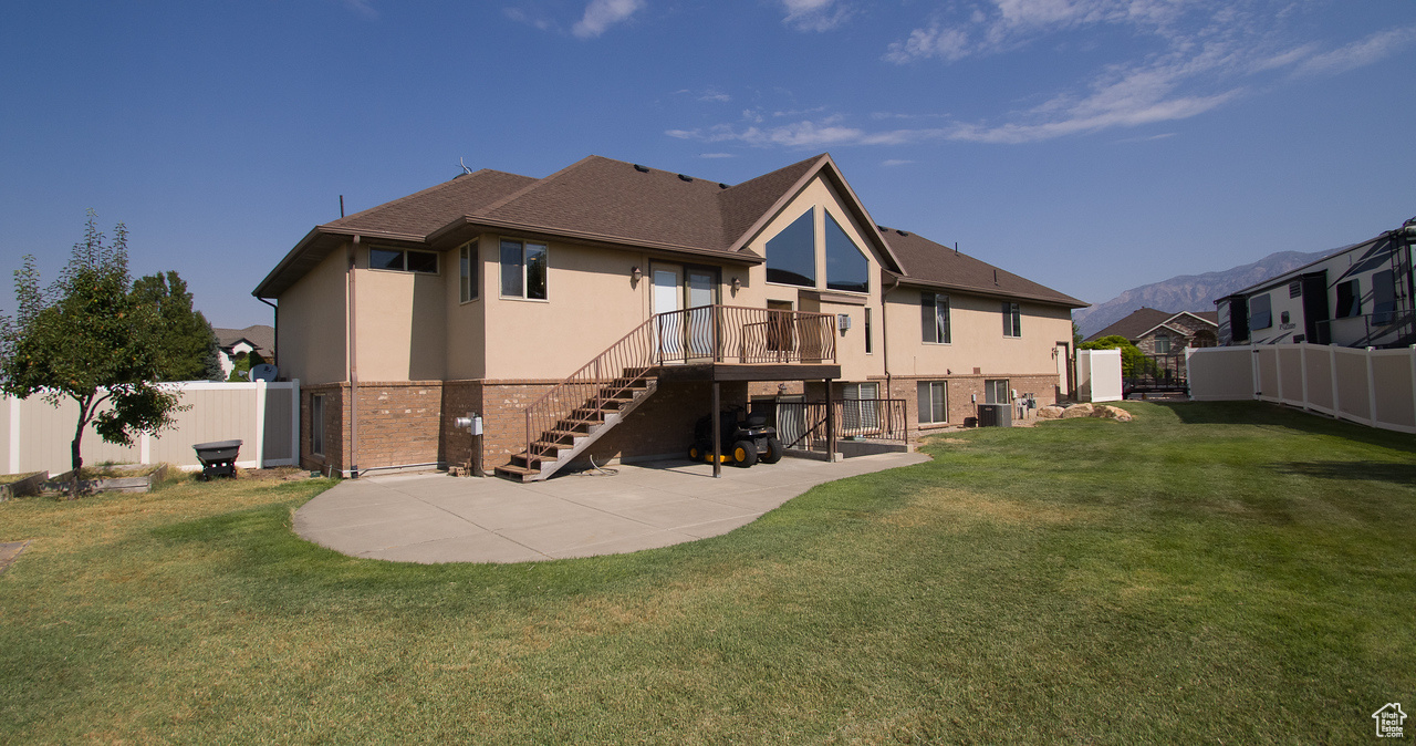 Rear view of house with a mountain view, a patio, and a yard