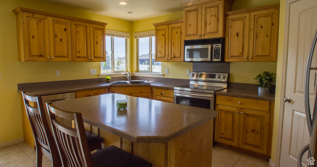 Kitchen featuring sink, appliances with stainless steel finishes, a center island, and light tile patterned floors