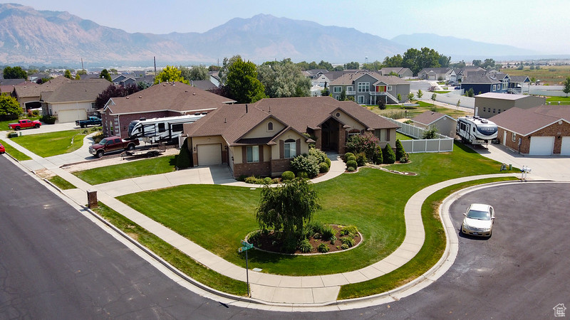 View of front facade featuring a garage, a mountain view, and a front lawn