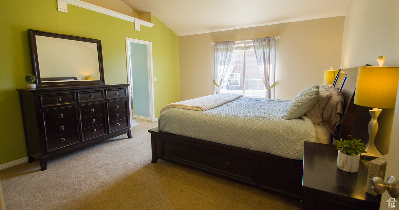 Primary Bedroom with light colored carpet and vaulted ceiling