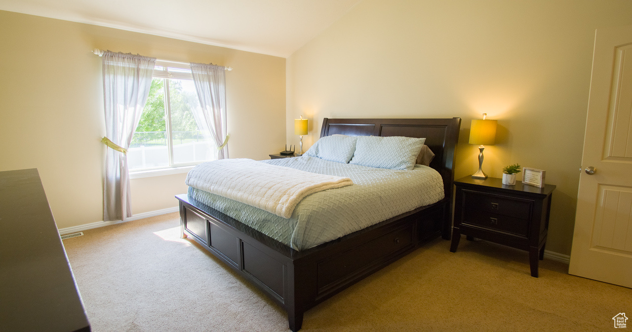 Primary Bedroom featuring lofted ceiling and light colored carpet