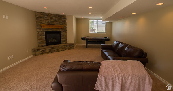 Living room featuring carpet and a stone fireplace