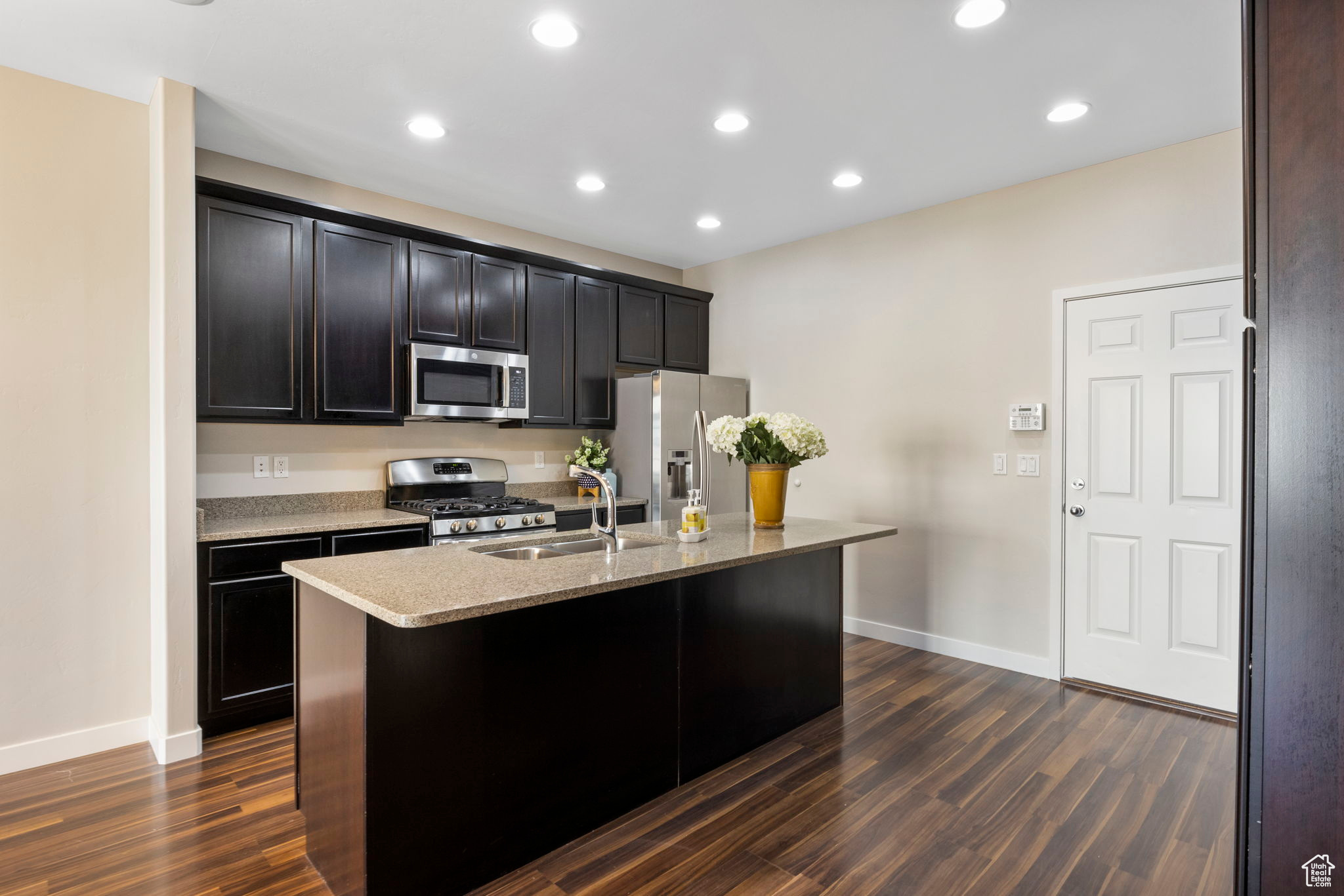 Kitchen featuring sink, appliances with stainless steel finishes, dark hardwood / wood-style flooring, and a kitchen island with sink