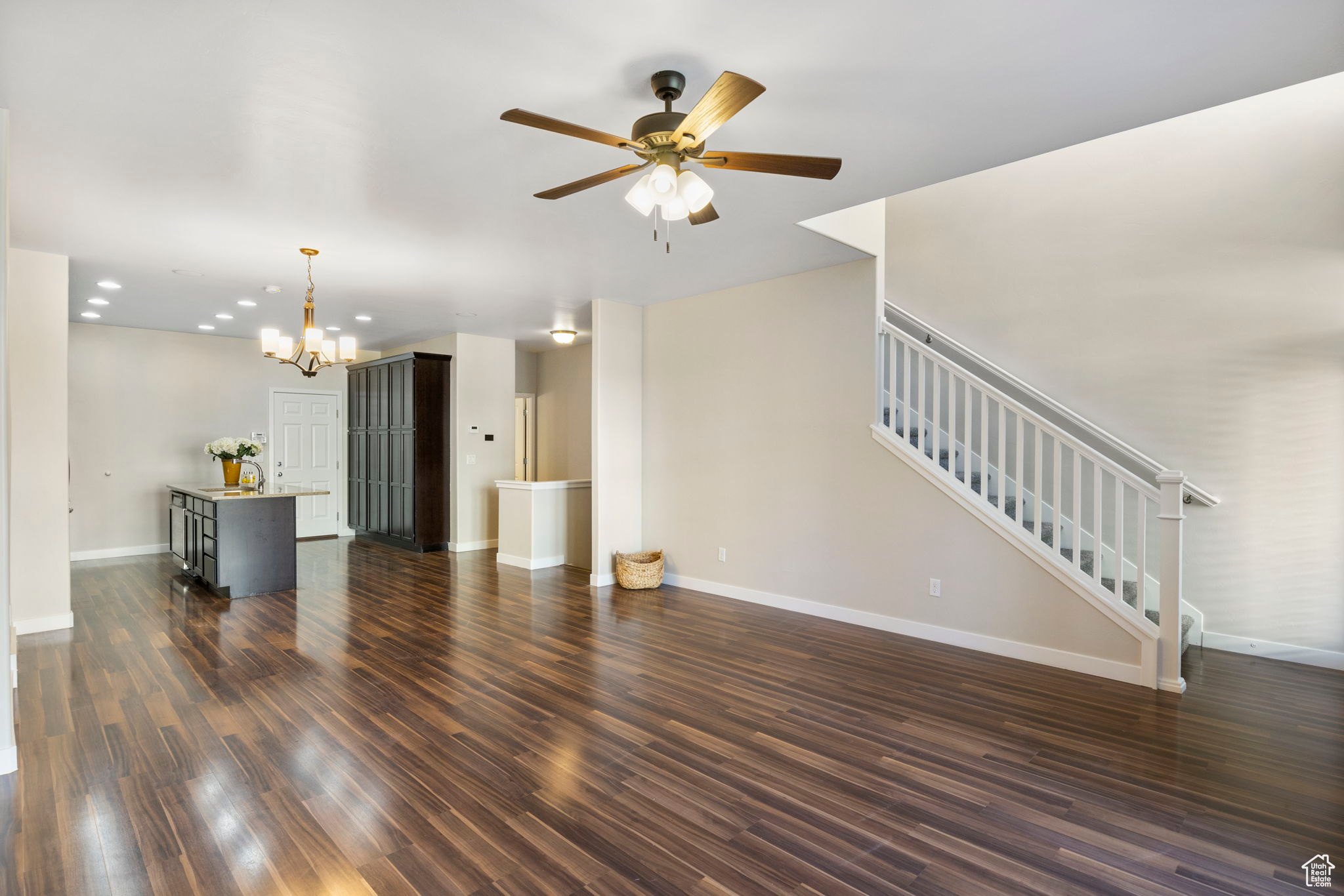 living room with dark wood-type flooring and ceiling fan with notable chandelier