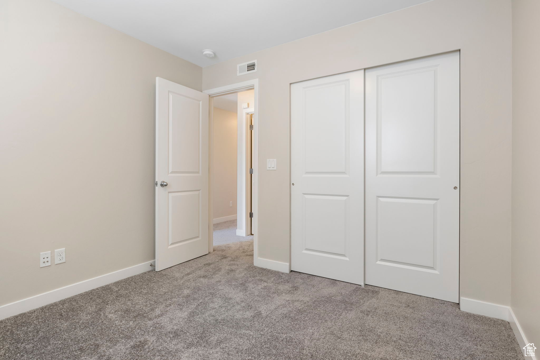 Unfurnished bedroom featuring a closet and light colored carpet