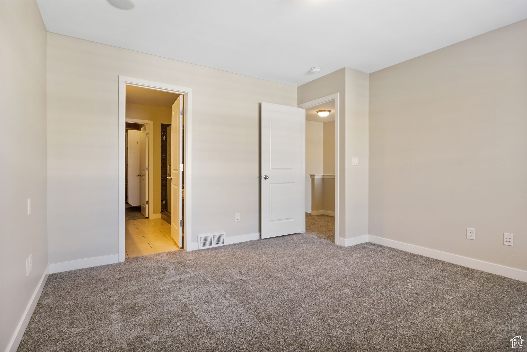 Unfurnished bedroom with light carpet and connected bathroom