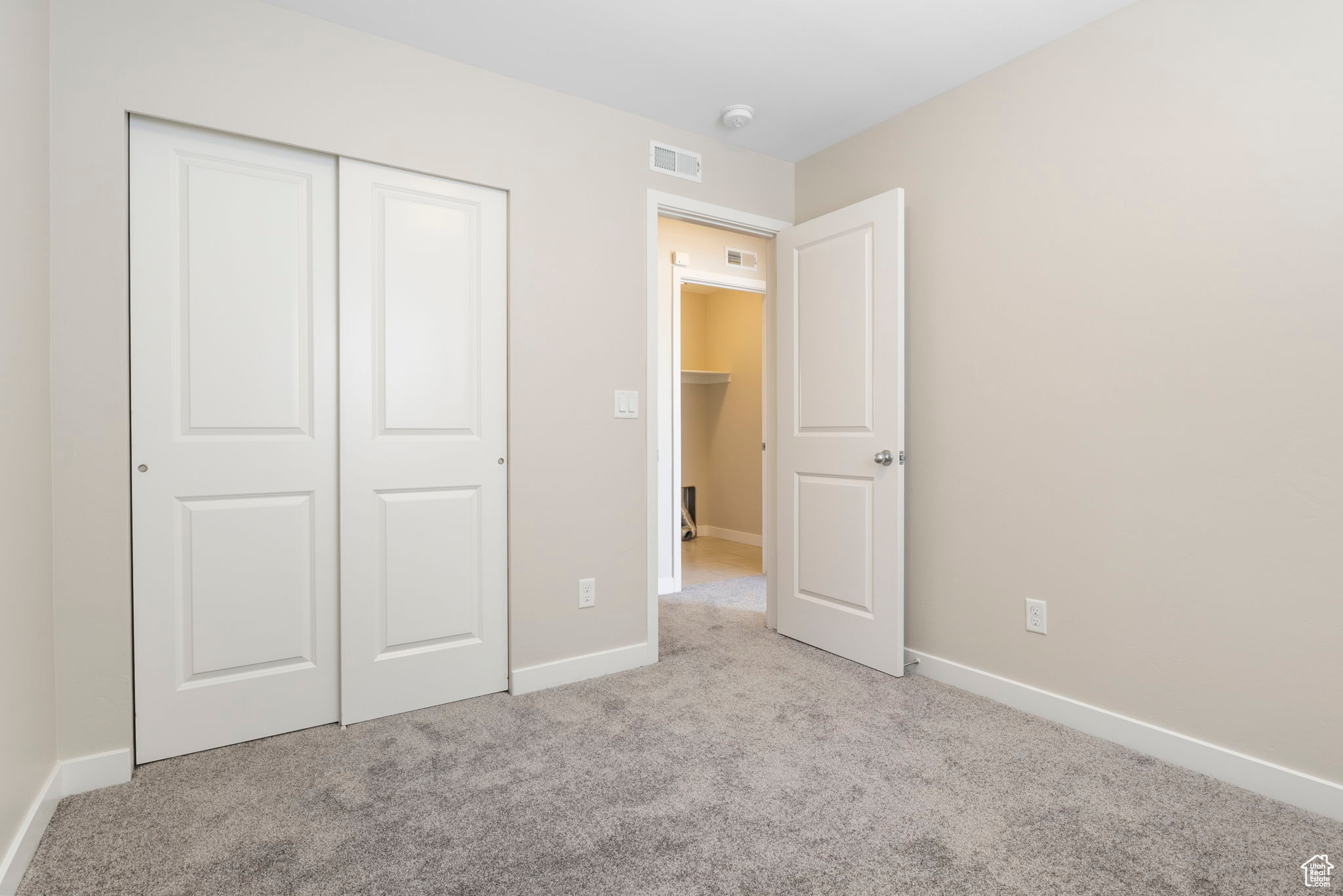 Unfurnished bedroom featuring light colored carpet and a closet