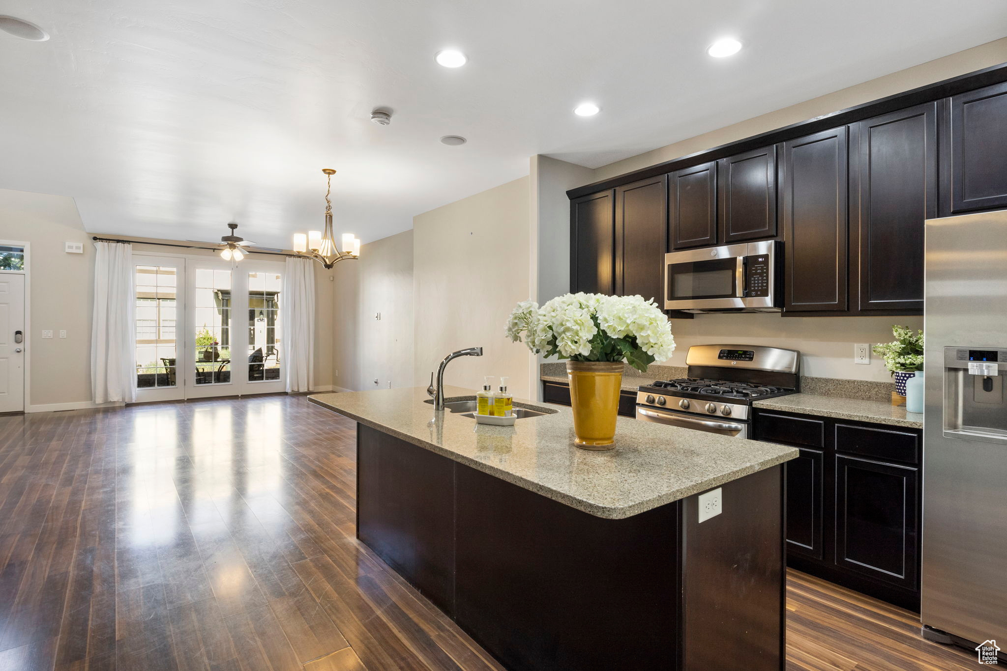 Kitchen featuring dark hardwood / wood-style floors, stainless steel appliances, light stone countertops, and sink