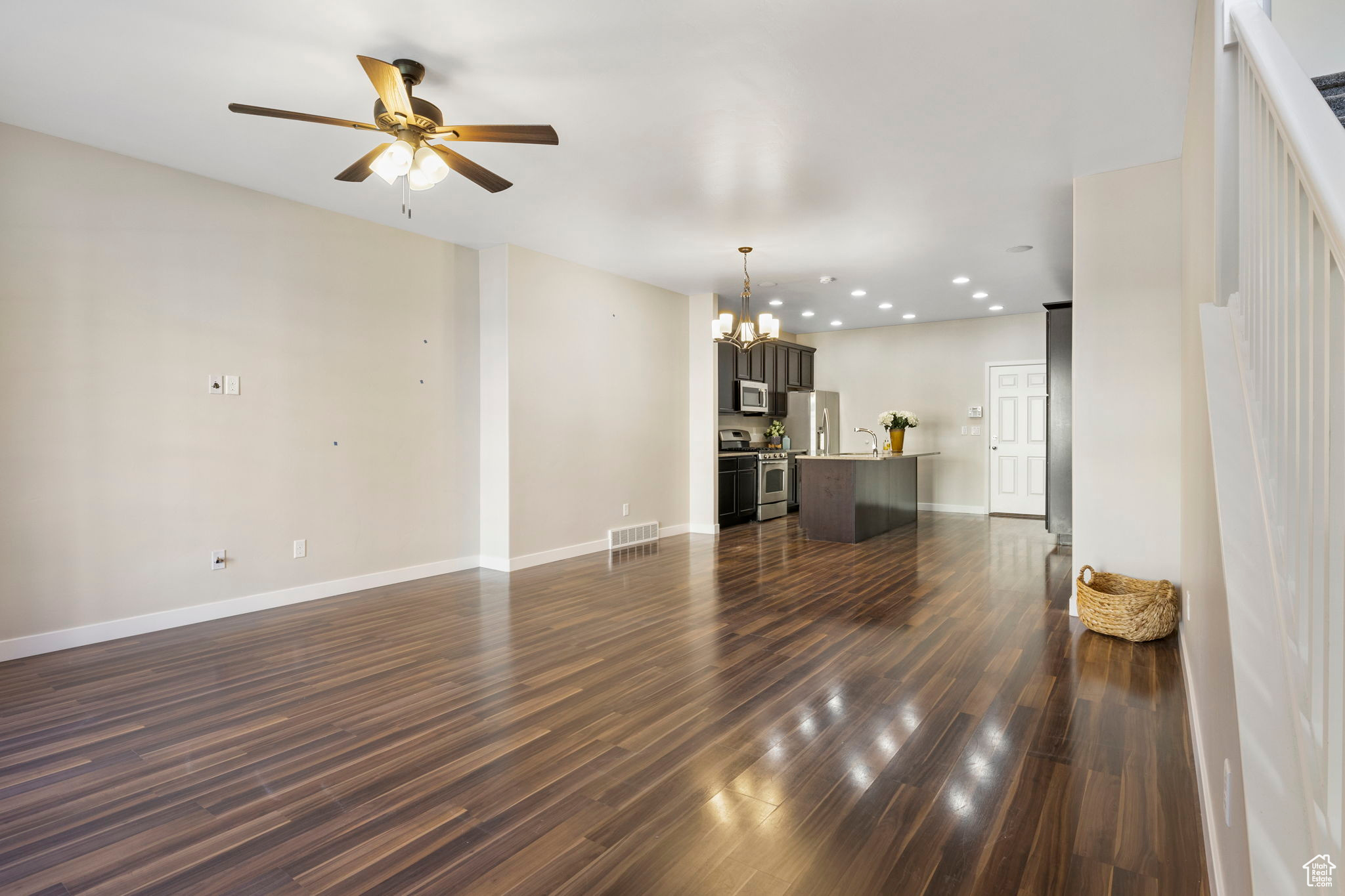 Unfurnished living room featuring ceiling fan with notable chandelier, dark hardwood / wood-style flooring, and sink