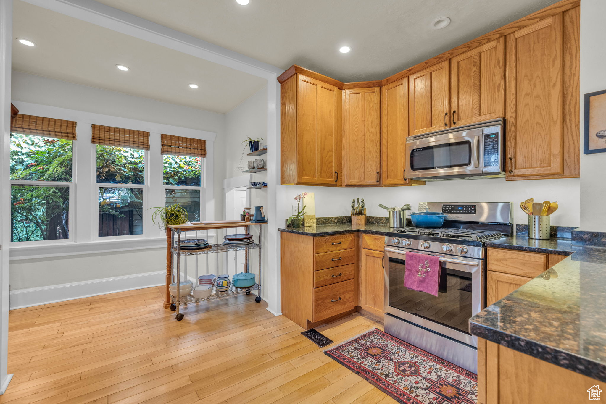 Kitchen featuring appliances with stainless steel finishes, light hardwood / wood-style flooring, and dark stone counters