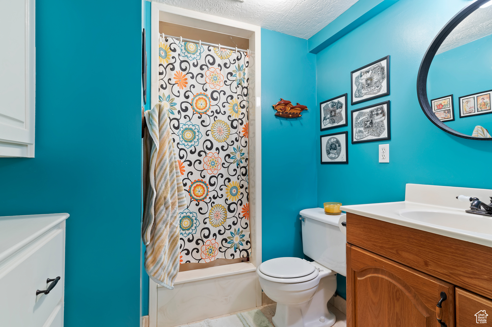 Bathroom featuring a textured ceiling, tile patterned flooring, vanity, and toilet