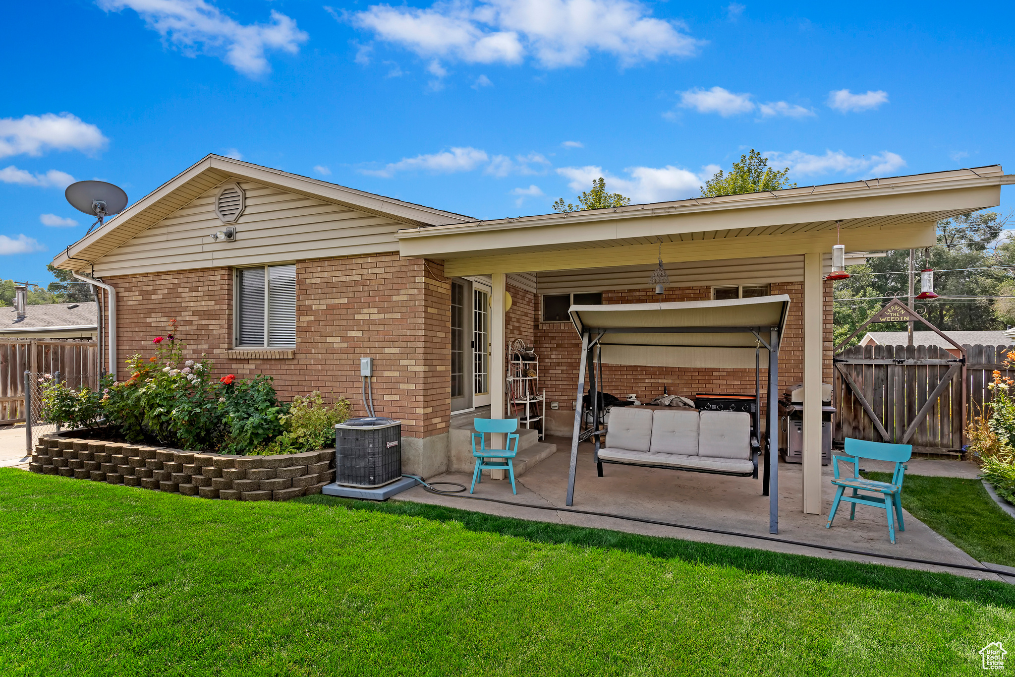 Rear view of house with central AC, a patio area, and a lawn