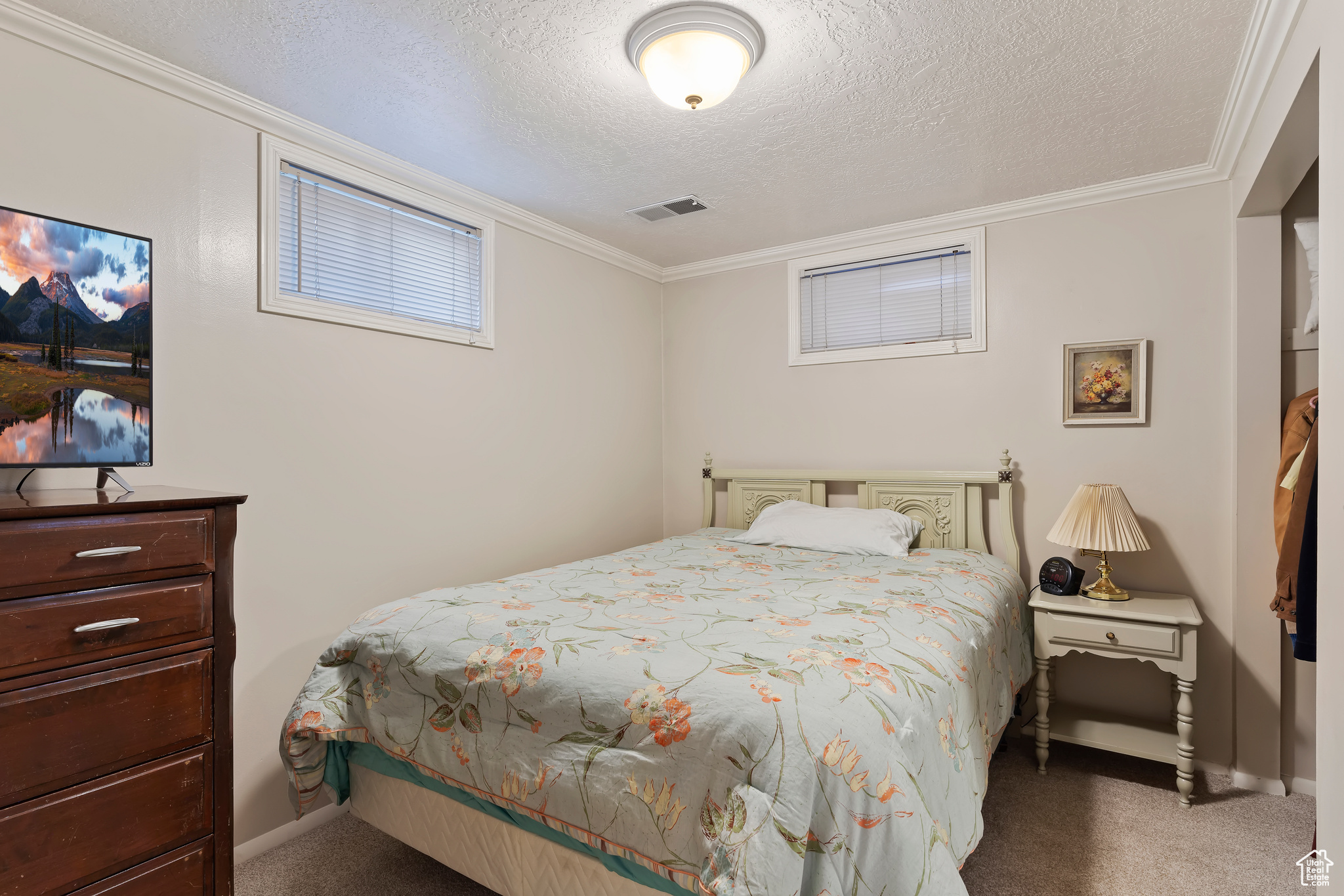 Carpeted bedroom with a textured ceiling and ornamental molding