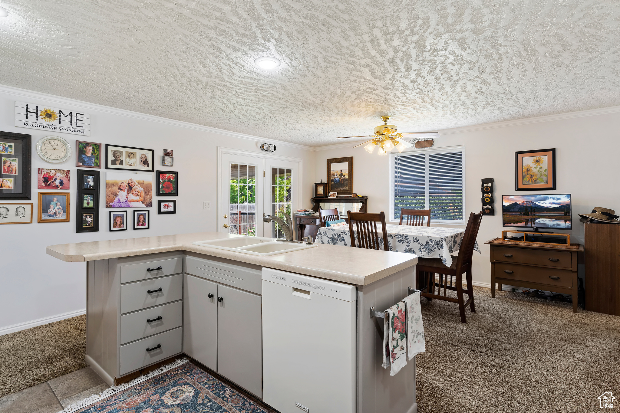 Kitchen with dishwasher, ceiling fan, sink, ornamental molding, and tile patterned flooring