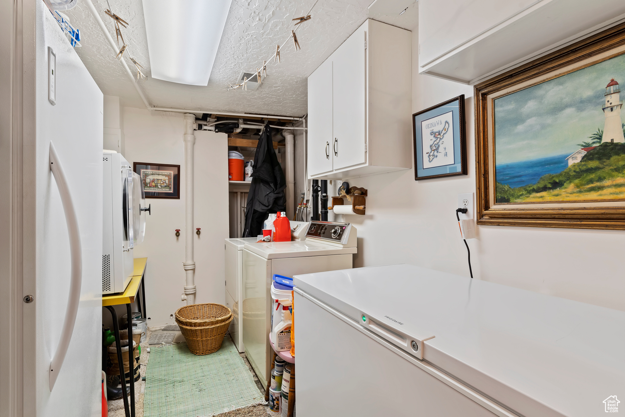 Clothes washing area with cabinets, a textured ceiling, and washing machine and dryer