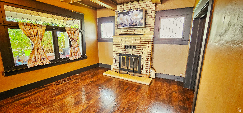 Living room featuring a fireplace, beam ceiling, and dark wood-type flooring