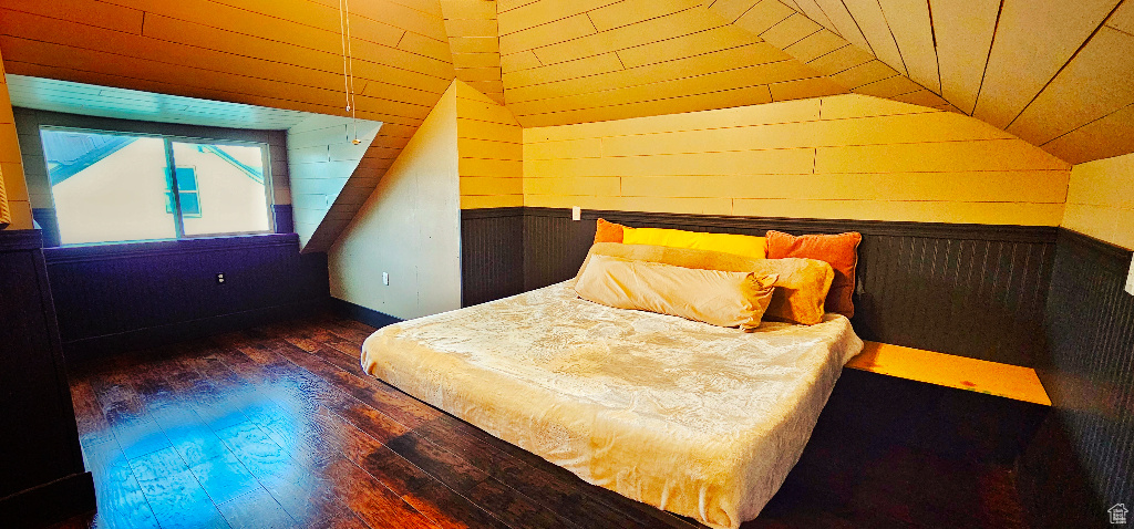 Bedroom featuring wood walls, dark hardwood / wood-style flooring, and lofted ceiling