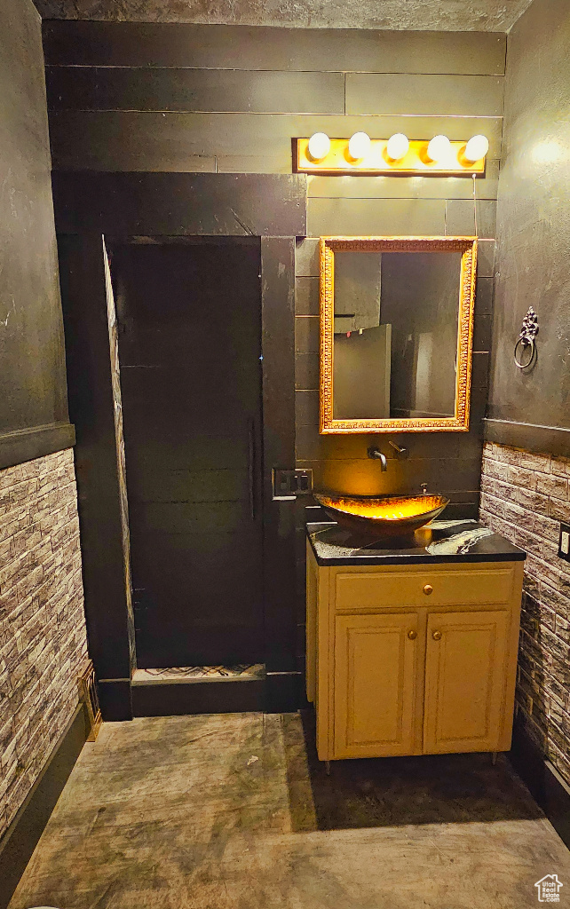 Bathroom featuring vanity, concrete floors, and brick wall