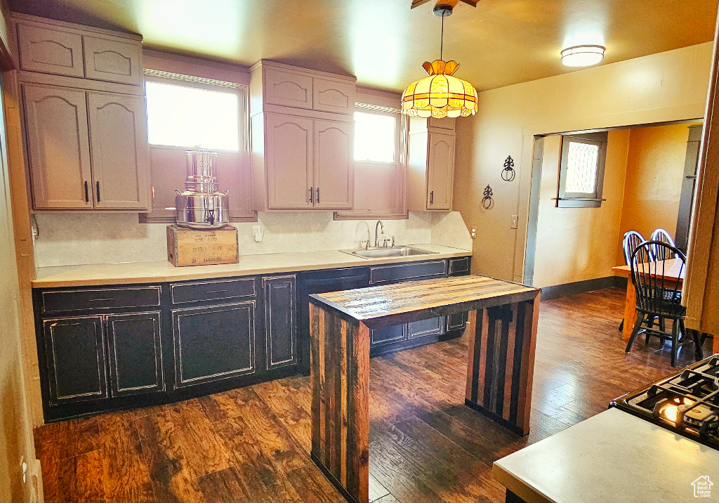 Kitchen with cooktop, dark hardwood / wood-style floors, sink, and hanging light fixtures