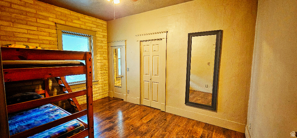 Bedroom with brick wall and dark hardwood / wood-style floors