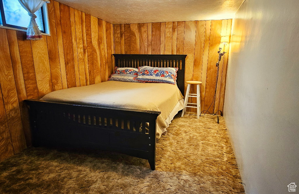 Bedroom featuring wood walls, dark carpet, and a textured ceiling