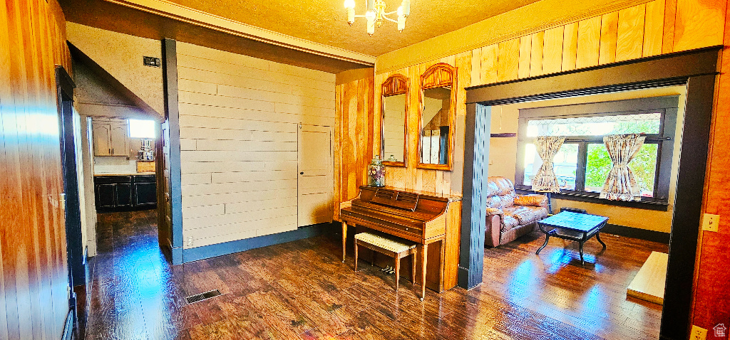 Corridor featuring wood walls, dark hardwood / wood-style flooring, and a chandelier